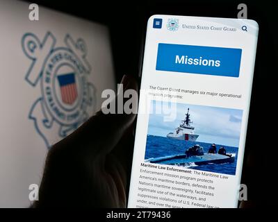 Person, die ein Handy hält, mit Webseite der United States Coast Guard (USCG) vor der Robbe. Konzentrieren Sie sich auf die Mitte des Telefondisplays. Stockfoto