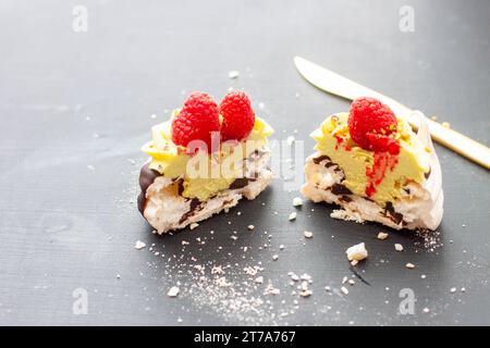 Nahaufnahme von Mini-pavlova-Kuchen mit Pistazien- und Schokoladenfüllung. Desserts mit Schlagsahne und frischer Himbeere Stockfoto