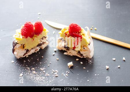 Nahaufnahme von Mini-pavlova-Kuchen mit Pistazien- und Schokoladenfüllung. Desserts mit Schlagsahne und frischer Himbeere Stockfoto