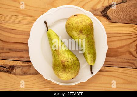 Zwei reife Birnen mit Keramikplatte auf einem Holztisch, Makro, Draufsicht. Stockfoto