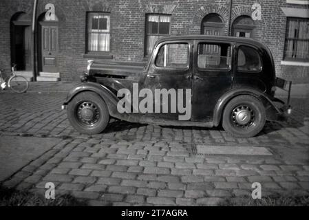 1950er Jahre, historisch, ein Auto einer erhabenen Ära, zerschlagen, auf einer Kopfsteinpflasterstraße mit kleinen viktorianischen Reihenhäusern geparkt, Oldham, Manchester, England, Großbritannien. Stockfoto
