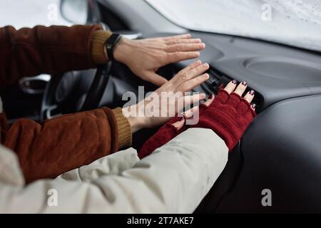 Junge Paare in Winterkleidung, die Hände halten, während sie während der Familienreise im Winter auf dem Vordersitz sitzen Stockfoto