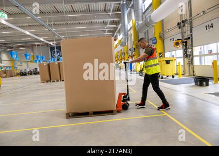 Erding, Deutschland. November 2023. Bei der offiziellen Eröffnung des Amazon Sortierzentrums in Erding bewegt ein Mitarbeiter von Amazon Waren. Quelle: Peter Kneffel/dpa/Alamy Live News Stockfoto