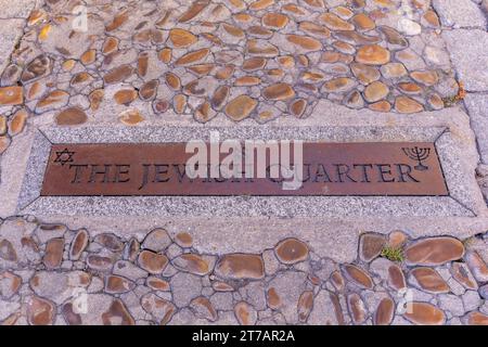 Toledo, Spanien, 08.10.21. Das Metallschild des jüdischen Viertels, eingebettet in die Kopfsteinpflasterstraße von Toledo, Spanien. Nahansicht. Stockfoto