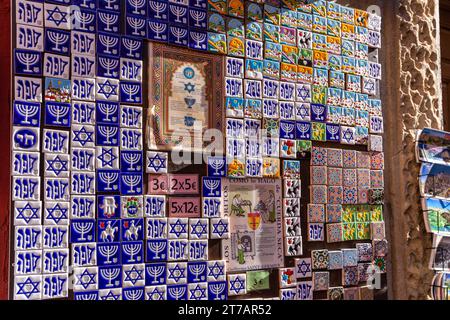 Toledo, Spanien, 08.10.21. Souvenirshop mit bunten Magnetfliesen im Kühlschrank mit jüdischen Symbolen: Menora, Davidstern und Symbol des Netzwerks Stockfoto