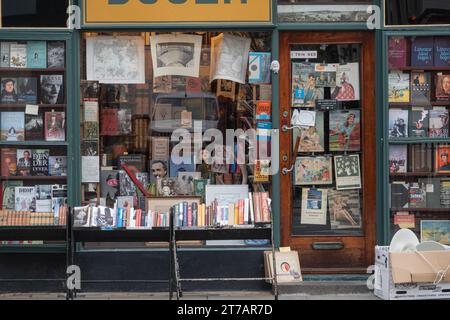 Vorderes Fenster eines kleinen Antiquariats, das Bücher, Karten, Zeitschriften, Drucke und alte Karten verkauft. Kopenhagen, Dänemark - 13. November 2023. Stockfoto