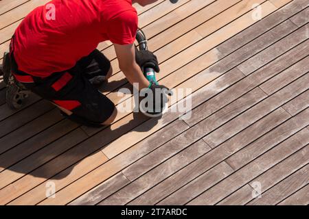 Reinigung der Terrasse mit einem Elektroschleifer - professioneller Decksreiniger auf der Holzoberfläche der Terrasse, Holzbretter vor und nach dem Schleifen Stockfoto