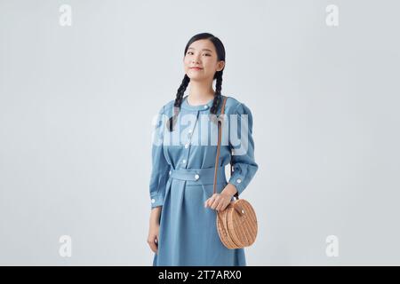 Schöne lächelnde junge Frau im Jeanskleid, Tasche isoliert auf weißem Hintergrund Stockfoto