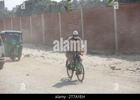 Dhaka, Wari, Bangladesch. November 2023. Starke Staubverschmutzung trägt zu den Problemen der Pendler auf der Straße bei, am 14. November 2023 in Dhaka, Bangladesch. Die Staubverschmutzung erreicht in Dhaka ein alarmierendes Stadium, und aufgrund der schlechten Luftqualität treten jedes Jahr viele Todesfälle sowie mehrere Millionen Krankheitsfälle auf. Dhaka hat sich schon lange mit Problemen der Luftverschmutzung auseinandergesetzt. Seine Luftqualität wird im Winter meist ungesund und und verbessert sich im Monsun. Mit dem Aufkommen des Winters beginnt die Luftqualität der Stadt aufgrund der massiven Freisetzung von Schadstoffpartikeln aus den Bauarbeiten, rund, drastisch zu verschlechtern Stockfoto