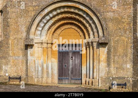 Eingang aus dem 12. Jahrhundert mit Rollen- und Chevron-Formteilen an der normannischen Kirche St. Michael im Cotswold-Dorf Guiting Power, Gloucestershire, Engla Stockfoto