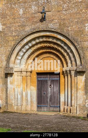 Eingang aus dem 12. Jahrhundert mit Rollen- und Chevron-Formteilen an der normannischen Kirche St. Michael im Cotswold-Dorf Guiting Power, Gloucestershire, Engla Stockfoto