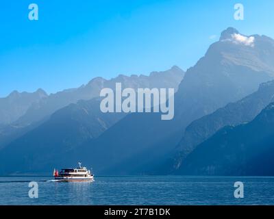 Umrisse der Berge am schweizer Urnersee im tagsüber trüben Licht. Touristenschiff auf dem See. Stockfoto