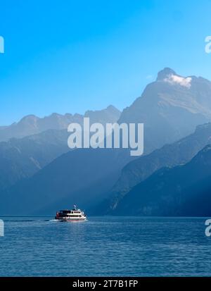 Umrisse der Berge am schweizerischen Urnersee - Luzerne See - im tagsüber trüben Licht. Touristenschiff auf dem See. Stockfoto