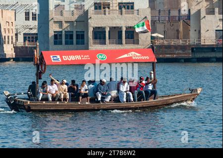Dubai, Vereinigte Arabische Emirate. Juli 2019 traditionelles lokales Wassertaxi, das an alten Häusern entlang des Dubai Creek, Deira, Vereinigte Arabische Emirate, vorbeifährt Stockfoto