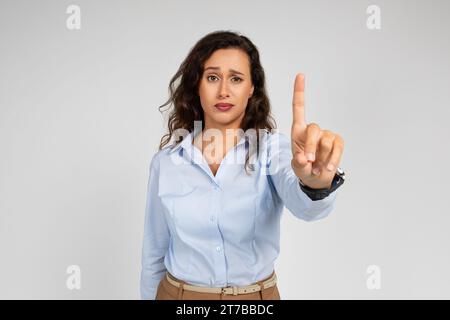 Ernsthafte, selbstbewusste, kaukasische Geschäftsfrau, Lehrerin in formeller Kleidung, zeigen mit dem Finger nach oben Stockfoto
