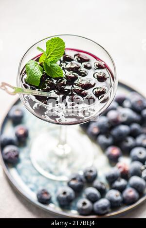 Nahaufnahme eines Glases Heidelbeermarmelade mit Minze auf einem Teller mit frischen Heidelbeeren Stockfoto