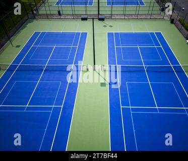 Ein Blick auf die Drohne mit Blick auf blaue Tennisplätze, die mit hellblauem Hintergrund für Pickleball mit Lichtern gesäumt sind. Stockfoto