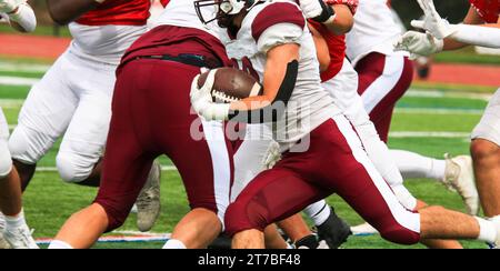 American Football Spieler läuft mit dem Ball hinter seinen Blockern während eines Spiels Stockfoto