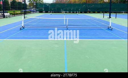 Zwei tragbare Pickleball-Netze auf einem Tennisplatz, die Platz für zwei Spiele bieten. Stockfoto