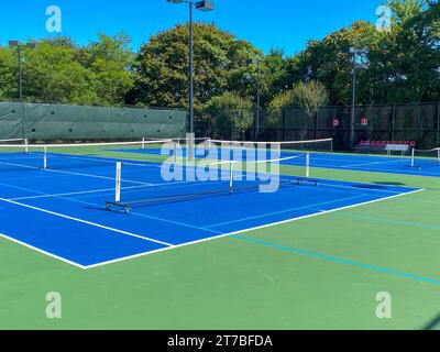 Tragbare Pickleball-Netze auf einem Tennisplatz bieten Platz für zwei Pickleball-Spiele pro Platz. Stockfoto