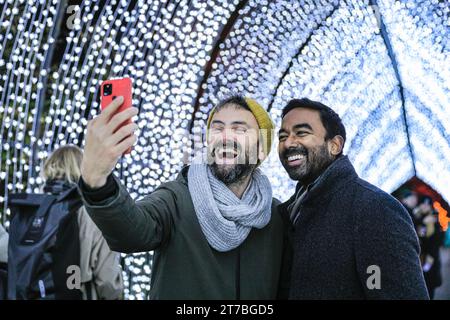 London, Großbritannien. November 2023. Zwei Kew-Modelle machen Selfies in der beliebten Lichtinstallation „Christmas Cathedral“, die von einem bogenförmigen Kirchenfenster inspiriert ist. Das beliebte „Christmas at Kew“ kehrt nach Kew Gardens in West London zurück. Der ursprüngliche festliche Pfad durch die Landschaft von Kew nach der Dunkelheit kehrt zum elften Jahr zurück und bietet neben zahlreichen neuen Lichtinstallationen zahlreiche saisonale Favoriten. Quelle: Imageplotter/Alamy Live News Stockfoto