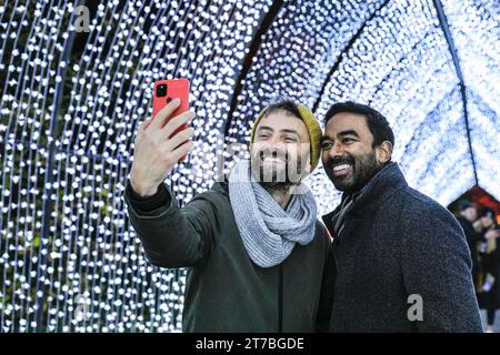 London, Großbritannien. November 2023. Zwei Kew-Modelle machen Selfies in der beliebten Lichtinstallation „Christmas Cathedral“, die von einem bogenförmigen Kirchenfenster inspiriert ist. Das beliebte „Christmas at Kew“ kehrt nach Kew Gardens in West London zurück. Der ursprüngliche festliche Pfad durch die Landschaft von Kew nach der Dunkelheit kehrt zum elften Jahr zurück und bietet neben zahlreichen neuen Lichtinstallationen zahlreiche saisonale Favoriten. Quelle: Imageplotter/Alamy Live News Stockfoto