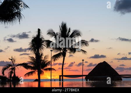 Sonnenaufgang über dem Golf von Mexiko spiegelt sich in den Infinity-Pool im Resort Stockfoto