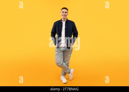 Stilvoller junger Kerl, der isoliert auf gelbem Hintergrund posiert Stockfoto