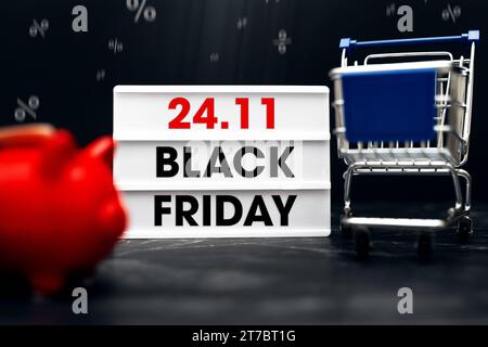 Augsburg, Bayern, Deutschland - 13. November 2023: 24,11 Black Friday-Schriftzug auf einem Leuchtkasten neben einem Einkaufswagen und einer roten Schweinebank. Angebote für die Black Friday Sales Event Concept FOTOMONTAGE *** 24,11 Black Friday Schriftzug auf einer Lightbox neben einem Einkaufswagen und einem roten Sparschwein. Angebote zum Black-Friday Verkaufsevent Konzept FOTOMONTAGE Credit: Imago/Alamy Live News Stockfoto