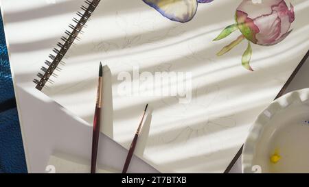 Aquarellmalerei. Pinsel und Papier aus nächster Nähe auf einem Tisch bei hellem Sonnenlicht vom Fenster. Kunst, Zeichnen lernen, Hobby-Konzept Stockfoto