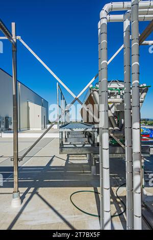 Ein Blick durch einen Rohrstützrahmen in Richtung eines adiabatischen Kondensators auf dem Dach eines CO2-Kühllagers (Industriekühlung) Stockfoto