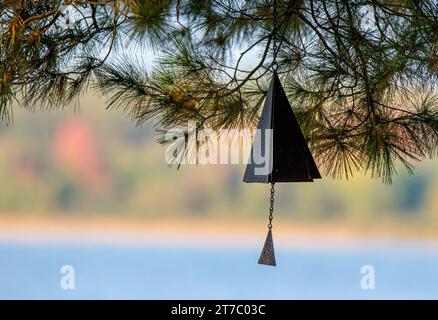 Windspiel aus Metall hängt in Kiefern mit See und Küste als Hintergrund im Chippewa National Forest im Norden von Minnesota, USA Stockfoto