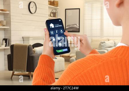 Frau, die Smart Home Control System über Anwendung auf Handy in Innenräumen, Nahaufnahme Stockfoto