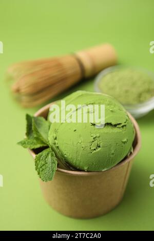 Papierbecher mit leckerem Matcha-Eis auf hellgrünem Hintergrund Stockfoto