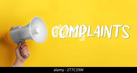 Mann mit Megaphon auf gelbem Hintergrund, Nahaufnahme. Wortbeschwerden, die vom Gerät ausgegeben werden. Bannerdesign Stockfoto
