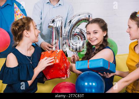 Lächelndes Portrait-Geburtstagskind mit Nummer 16 Folienballon-Geschenke Stockfoto