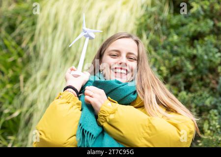 Junge Frau mit Windenergieanlage an einer Hauspflanzenwand als Umweltschutz Stockfoto