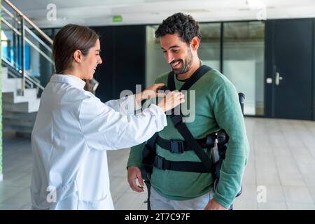 Mechanisches Exoskelett, Physiotherapeutin Ärztin mit Klebeband auf Behinderte mit Roboterskelett, Physiotherapie in einem modernen Krankenhaus Stockfoto