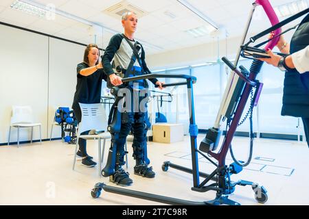 Mechanisches Exoskelett. Weibliche physiotherapeutische Assistentin beim Heben von Behinderten mit Roboterskelett. Futuristische Rehabilitation Stockfoto