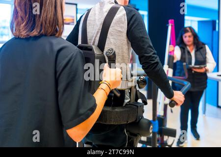 Mechanisches Exoskelett. Weibliche physiotherapeutische Assistentin hilft behinderten Menschen mit Roboterskelett beim Gehen. Futuristische Rehabilitation, Physi Stockfoto