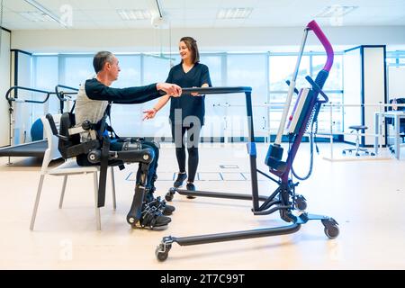 Mechanisches Exoskelett. Physiotherapie-Assistent, der Behinderte mit Roboterskelett zum Aufstehen hebt. Futuristische Rehabilitation, Physiotherapie in Stockfoto