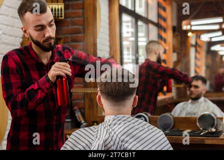 Friseur besprengt junge Mannhaare Stockfoto