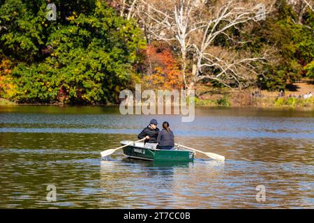 Ein paar Reihen ein hölzernes Boot im großen Teich des New York City Central Park im Herbst zwischen den wunderschönen, herbstlichen Bäumen. Stockfoto