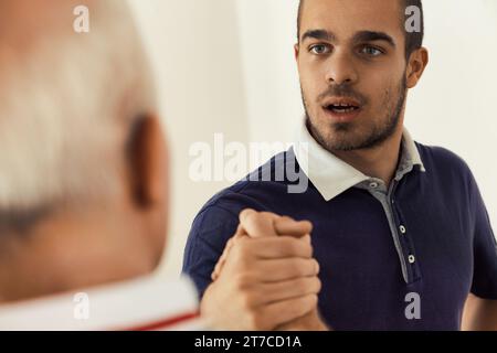 Intensiver Blick auf einen jungen Mann in einem Arm-Ringen-Handschlag, der Stärke und Respekt verkörpert Stockfoto