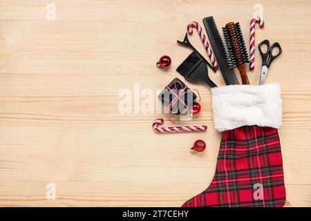 Komposition mit Weihnachtssocke, Friseurzubehör und Geschenkbox auf hölzernem Hintergrund Stockfoto