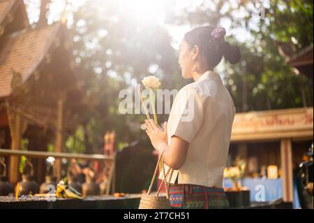 Eine wunderschöne asiatische Thai-Frau in einem traditionellen Thai-Lanna-Kleid wünscht sich und zollt Respekt vor dem Bild des Buddha in einem Tempel. Thailändische Kultur Stockfoto