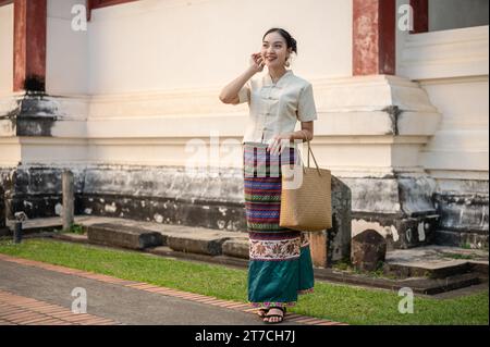 Ein Porträt einer wunderschönen jungen thailändischen-asiatischen Frau in einem traditionellen thailändischen und nordischen Kleid ist in einem wunderschönen Tempel. Thailändische Kultur, Buddhismus, kulturelle reise Stockfoto