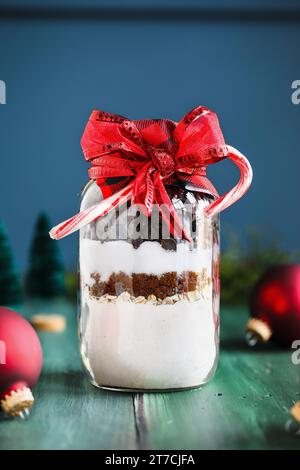 Geschenk von Chocolate Chip Cookie Teig Rezeptmischung von Zutaten zum Backen von Keksen zu Weihnachten. Gebunden mit einem roten Band und Zuckerstangen. Selektiv Stockfoto