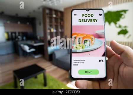 Bestellen und liefern Sie Lebensmittel online. Essen Sie vom Smartphone aus. Gerät auf blauem Hintergrund. Fast Food und schnelle Lieferung bei Online-Bestellungen Konzept. Bestellen Sie eine Mahlzeit Stockfoto
