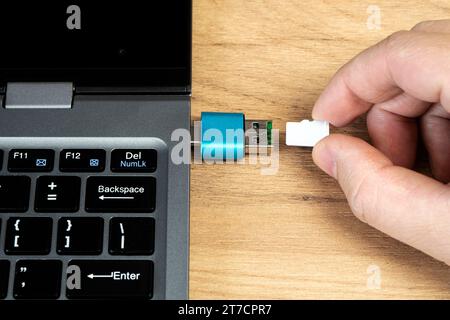 usb-Flashlaufwerk-Adapter für Micro-sd-Kartenanschluss an Laptop. microsd-Karte in der Hand eines Mannes Stockfoto